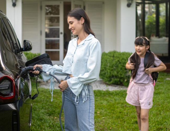 Mother and daughter waiting for the electric car to charge at home.